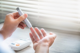 Person pricking their finger to test blood sugar.